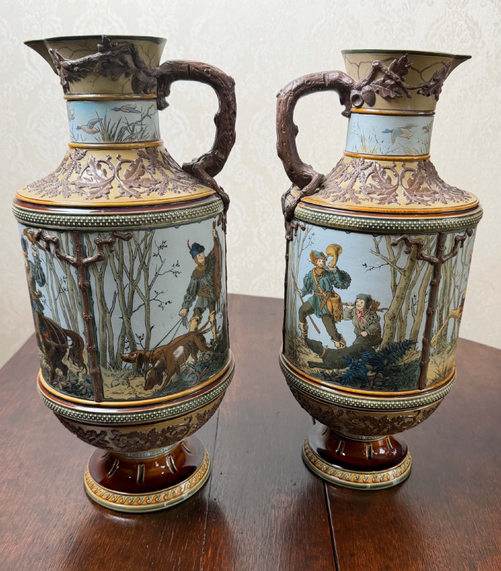 A pair of 19th-century Mettlach stoneware vases featuring sculpted branch handles, oak leaf relief decoration, and incised pictorial hunting scenes in blue and brown. View III