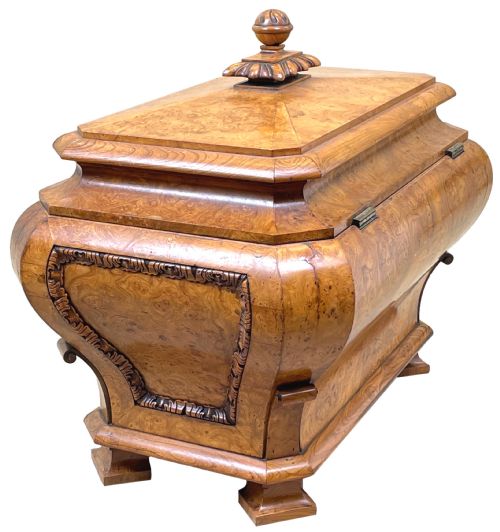 fig 3. An antique sarcophagus-shaped burr elm cellarette with a carved top finial, gadrooned moulding, and a brass keyhole escutcheon.
