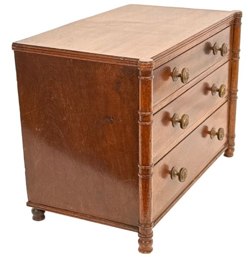 fig 1. A Regency period miniature mahogany chest featuring three graduated drawers with round knobs and reeded corner columns.