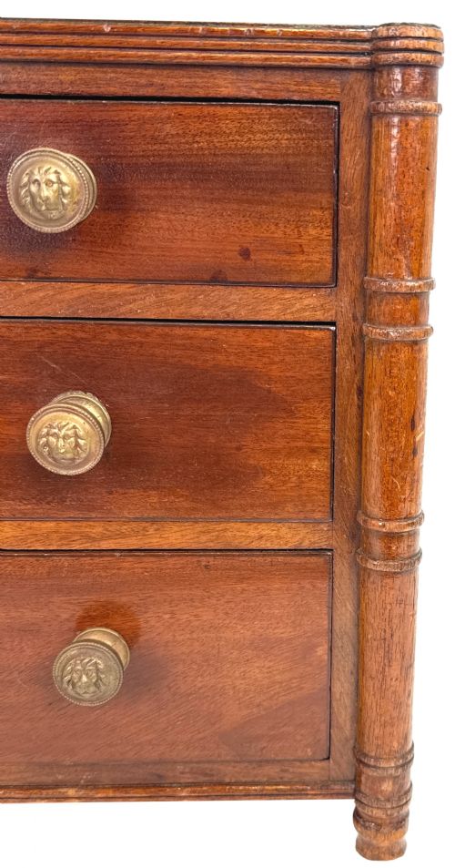 fig 4. A Regency period miniature mahogany chest featuring three graduated drawers with round knobs and reeded corner columns.