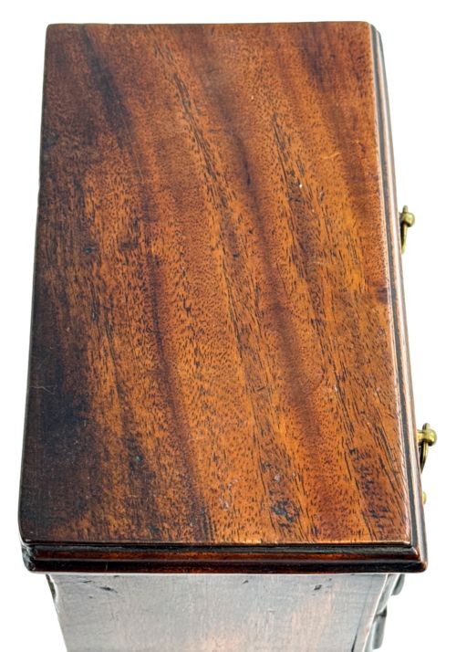 fig 1. A miniature 18th-century mahogany chest of drawers featuring two small drawers over three long drawers with brass ring drop handles and bracket feet.