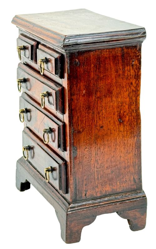 fig 3. A miniature 18th-century mahogany chest of drawers featuring two small drawers over three long drawers with brass ring drop handles and bracket feet.