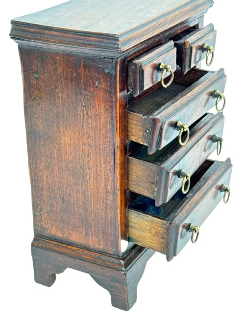 fig 4. A miniature 18th-century mahogany chest of drawers featuring two small drawers over three long drawers with brass ring drop handles and bracket feet.