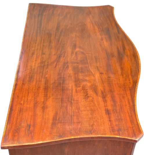 fig 1. A Georgian style mahogany chest of drawers featuring a serpentine front, four graduated drawers with brass ring handles, and bracket feet.