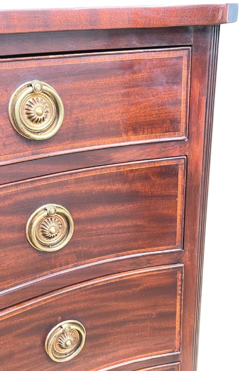 fig 3. A Georgian style mahogany chest of drawers featuring a serpentine front, four graduated drawers with brass ring handles, and bracket feet.