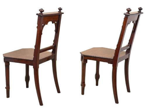 fig 2. A pair of Victorian mahogany hall chairs featuring carved shield backrests, open architectural arches, turned finials, and solid wooden seats.