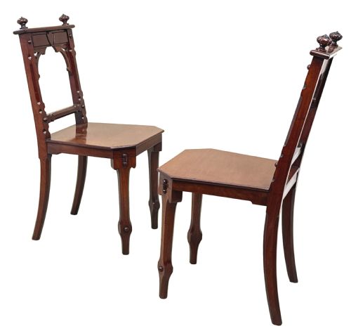 fig 5. A pair of Victorian mahogany hall chairs featuring carved shield backrests, open architectural arches, turned finials, and solid wooden seats.