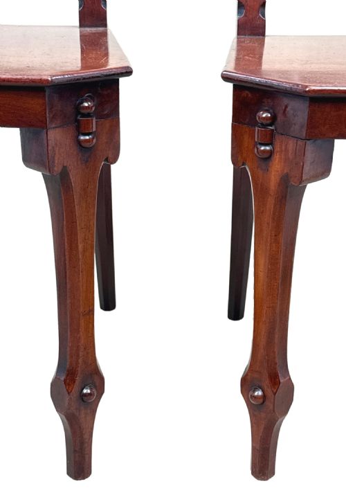 fig 6. A pair of Victorian mahogany hall chairs featuring carved shield backrests, open architectural arches, turned finials, and solid wooden seats.