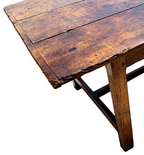 fig 3. An 18th-century English farmhouse dining table crafted from warm brown oak with a wide three-plank top, plain apron, and an H-stretcher base.