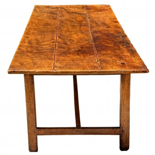 fig 4. An 18th-century English farmhouse dining table crafted from warm brown oak with a wide three-plank top, plain apron, and an H-stretcher base.