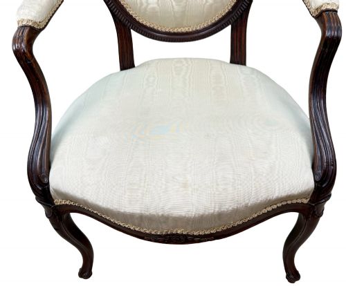 fig 1. An 18th-century Georgian mahogany salon chair featuring an oval back rest, carved wooden frame, and cream silk upholstery.