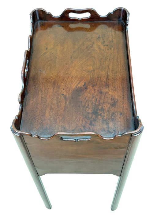 fig 2. An 18th-century Georgian mahogany bedside table with a wavy gallery top featuring pierced hand cutouts, an open shelf compartment, and four square legs.