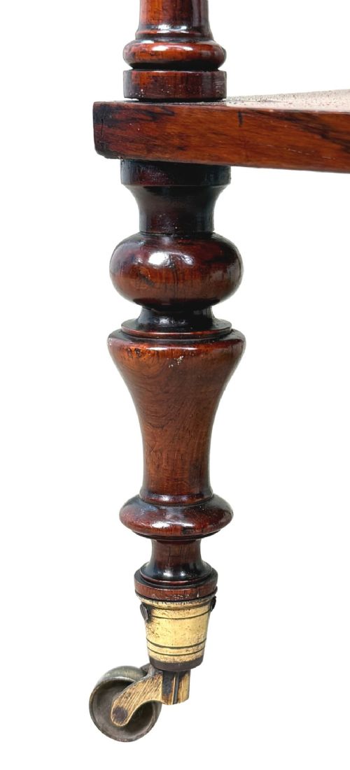 A mid-19th-century rosewood three-tier whatnot with turned spindles, finials, and brass castors. View VIII