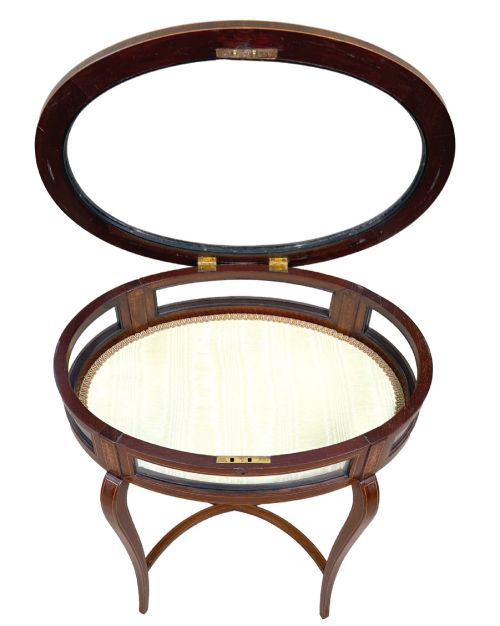 fig 1. An oval late 19th-century mahogany bijouterie display table featuring glass side panels, inlaid floral marquetry, slender cabriole legs, and a cross stretcher.