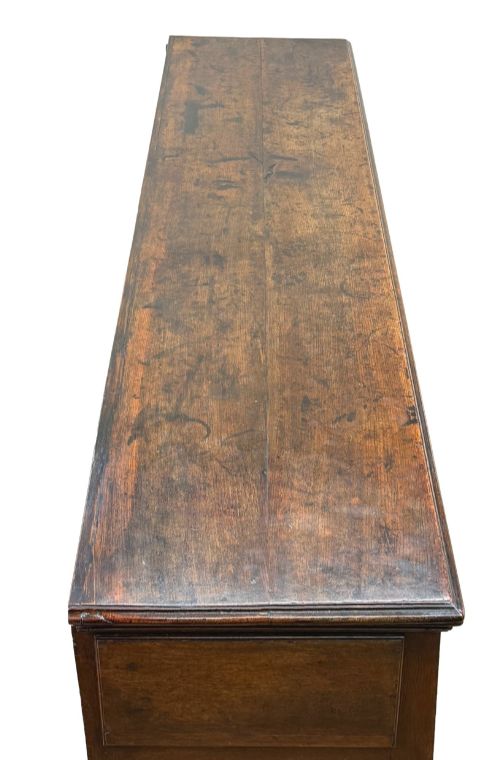 fig 3. An early eighteenth-century oak dresser base featuring three drawers with brass drop handles, brass keyhole escutcheons, turned front legs, and a dark brown finish.