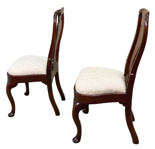 fig 3. A pair of early 18th-century Queen Anne walnut side chairs featuring vase-shaped back splats, curved cabriole front legs, and cream upholstered drop-in seats.