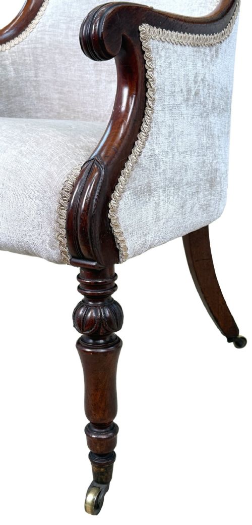 fig 1. A 19th-century English Regency mahogany tub armchair with cream upholstery, scrolled armrests, turned legs, and brass castors.