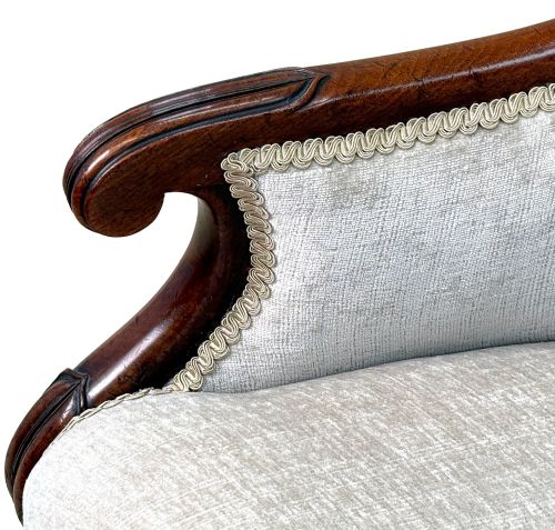 fig 3. A 19th-century English Regency mahogany tub armchair with cream upholstery, scrolled armrests, turned legs, and brass castors.