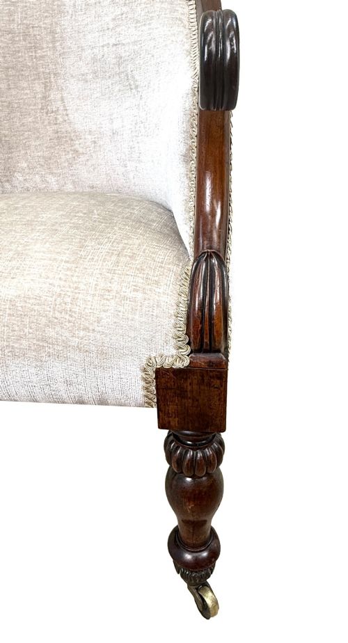 fig 1. A 19th-century Regency period rosewood tub library armchair upholstered in cream fabric with turned legs and brass castors.