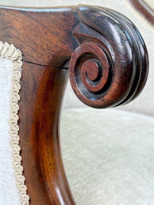 fig 5. A 19th-century Regency period rosewood tub library armchair upholstered in cream fabric with turned legs and brass castors.
