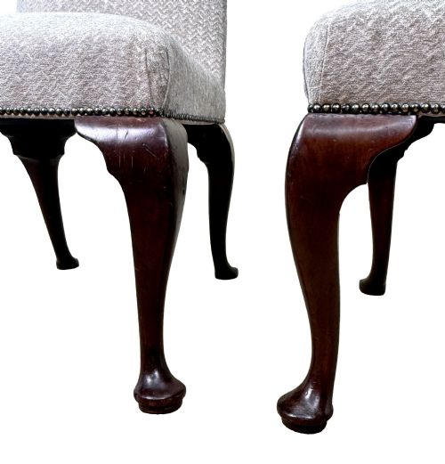 fig 2. A pair of Georgian walnut side chairs featuring cream textured upholstery and carved cabriole legs ending in pad feet.
