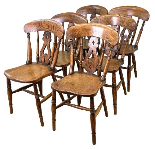 fig 4. A set of six Victorian wooden Windsor dining chairs featuring shaped crest rails, pierced back splats, contoured saddle seats, and turned legs.
