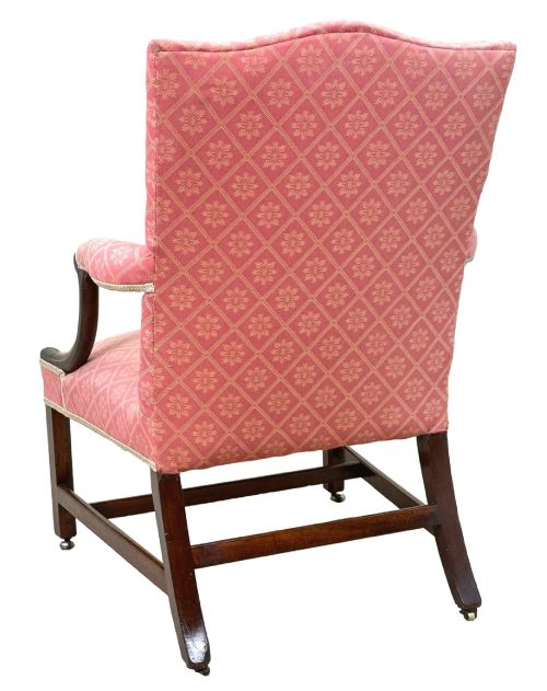 fig 3. An 18th-century Georgian mahogany Gainsborough armchair with red patterned upholstery, curved carved arm supports, an H-stretcher frame, and brass castors.