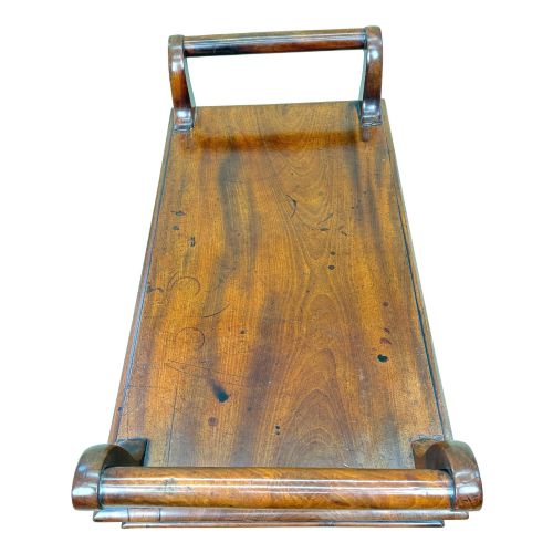fig 3. A mid-19th-century mahogany window seat with turned legs, a flat wooden seat, and curved end handles.