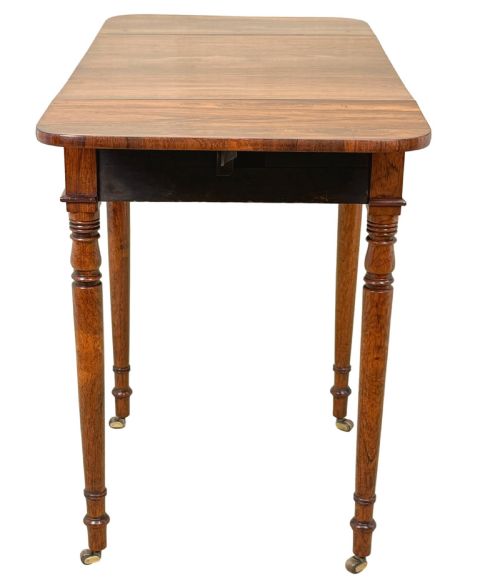 fig 2. An early 19th-century Regency rosewood Pembroke table featuring extended drop leaves, turned legs on brass castors, and a single frieze drawer with brass knobs.