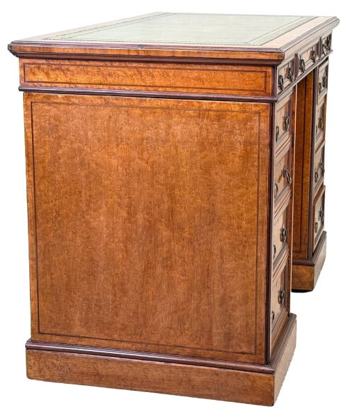 fig 2. A mid-19th-century English birdseye maple pedestal desk featuring a green leather writing surface, multiple drawers with brass ring drop handles, and a plinth base.
