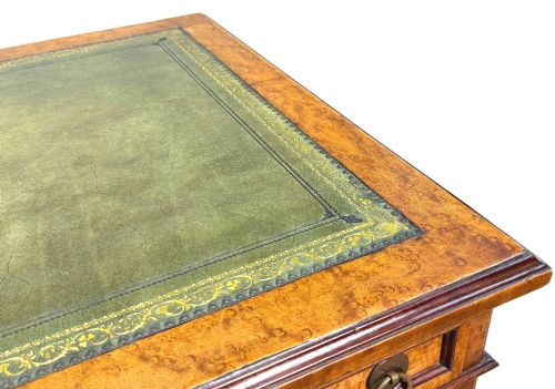 fig 5. A mid-19th-century English birdseye maple pedestal desk featuring a green leather writing surface, multiple drawers with brass ring drop handles, and a plinth base.