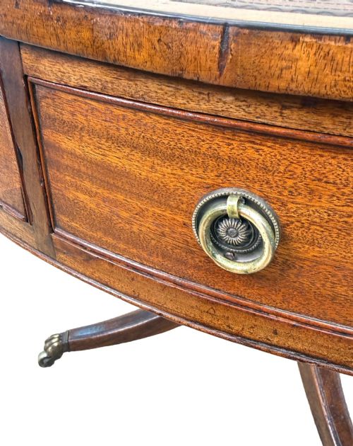 fig 2. A circular Georgian mahogany drum table featuring a brown leather top, frieze drawers with brass ring handles, and a pedestal base with four splayed legs on brass paw castors.