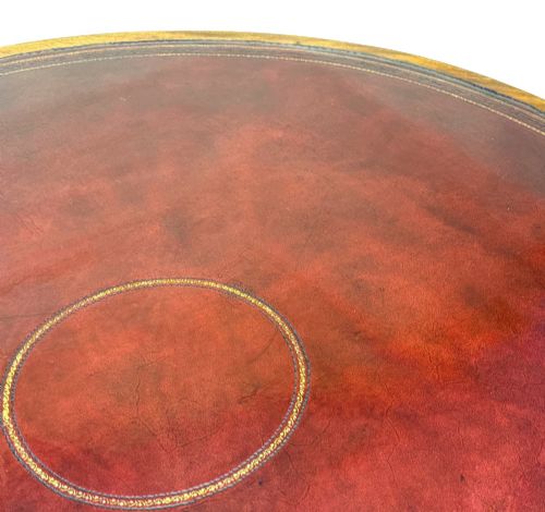 fig 3. A circular Georgian mahogany drum table featuring a brown leather top, frieze drawers with brass ring handles, and a pedestal base with four splayed legs on brass paw castors.