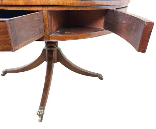 fig 4. A circular Georgian mahogany drum table featuring a brown leather top, frieze drawers with brass ring handles, and a pedestal base with four splayed legs on brass paw castors.