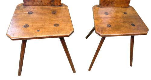 fig 5. A pair of mid-19th-century Swiss escabelle chairs crafted from warm brown fruitwood, featuring circular carved backrests with cut-out motifs and four splayed tapered legs.