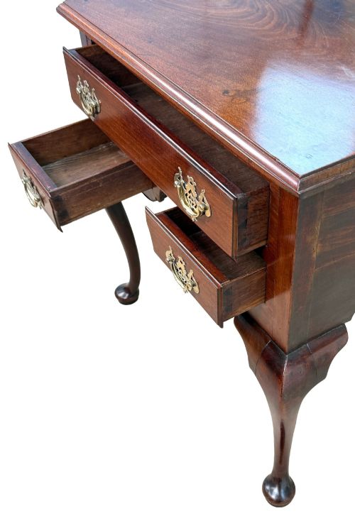 fig 3. An early Georgian mahogany lowboy table featuring three drawers with brass handles, a shaped apron, and four cabriole legs.