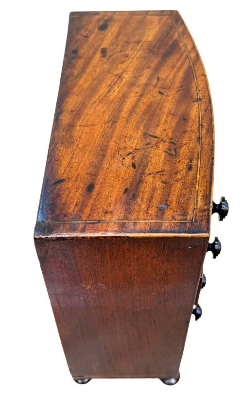 fig 2. An 18th-century Georgian mahogany miniature bowfront chest of drawers featuring boxwood inlay, four graduated drawers with turned wooden knobs, and low bun feet.