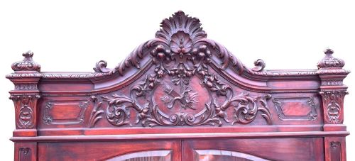 fig 2. A 19th-century dark mahogany display cabinet featuring a carved crest, glazed doors, and lower support with carved lion mask legs.