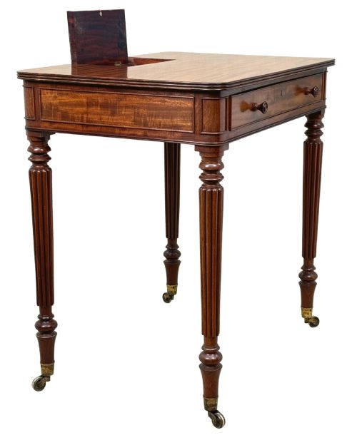 fig 2. A Regency mahogany chamber writing table featuring a single frieze drawer, fluted turned legs on brass castors, and an inset surface hatch.