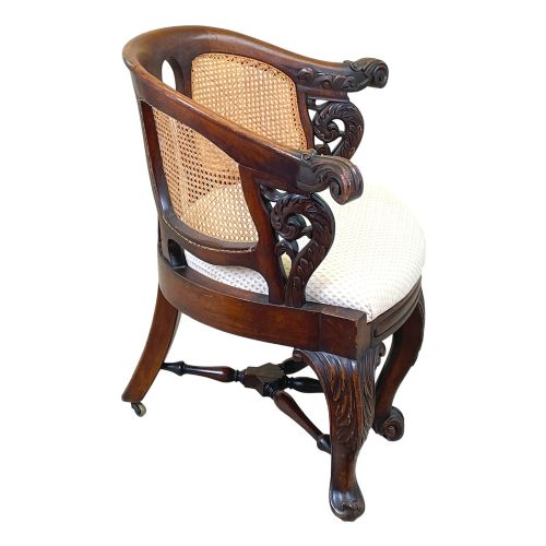 fig 1. A 19th-century mahogany Burgermeister desk chair featuring a curved backrest with woven cane panels, carved armrests, an upholstered cream seat, and cabriole legs.
