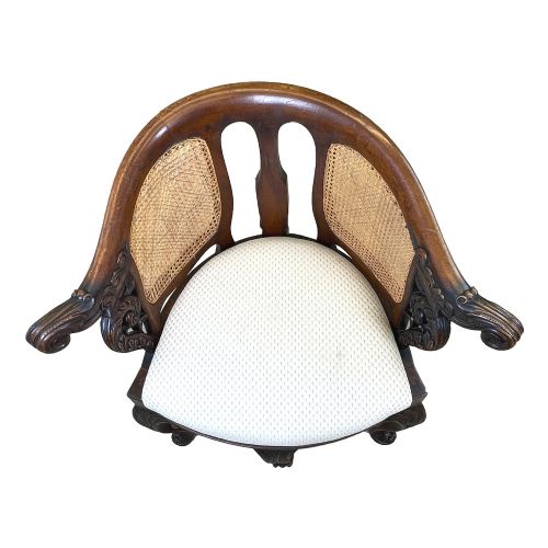 fig 2. A 19th-century mahogany Burgermeister desk chair featuring a curved backrest with woven cane panels, carved armrests, an upholstered cream seat, and cabriole legs.