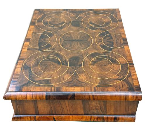 fig 1. A shallow rectangular William and Mary period wooden box with laburnum oyster veneered patterns, concentric circular stringing on the lid, and a brass keyhole escutcheon on the front panel.