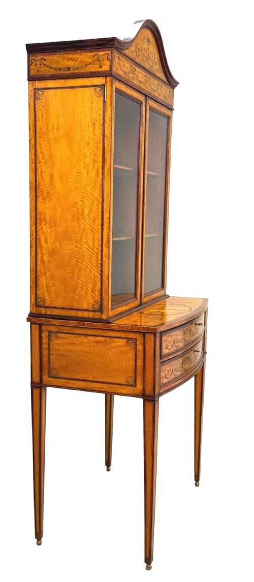 A 19th-century inlaid satinwood display cabinet featuring an arched cresting, glazed upper doors, marquetry frieze drawers, and square tapered legs. View VII