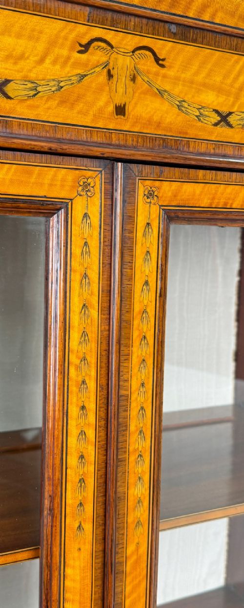 A 19th-century inlaid satinwood display cabinet featuring an arched cresting, glazed upper doors, marquetry frieze drawers, and square tapered legs. View VIII