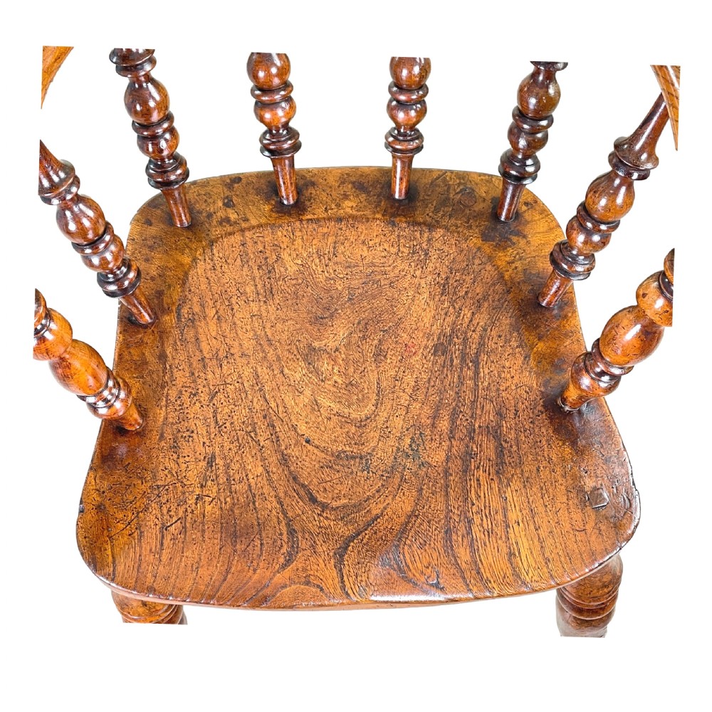 A 19th-century wooden clerk chair featuring a curved horseshoe backrest, turned spindles, a shaped saddle seat, and tall turned legs with double stretchers. View V