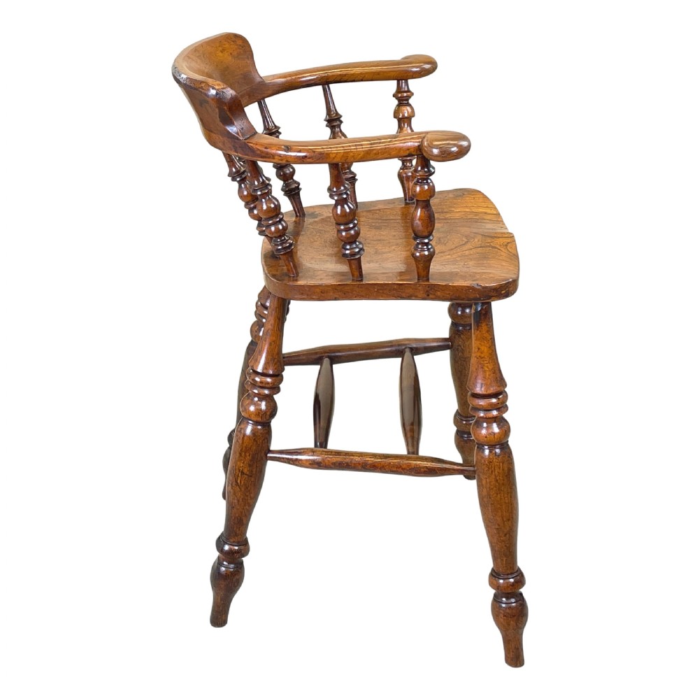 A 19th-century wooden clerk chair featuring a curved horseshoe backrest, turned spindles, a shaped saddle seat, and tall turned legs with double stretchers. View VI