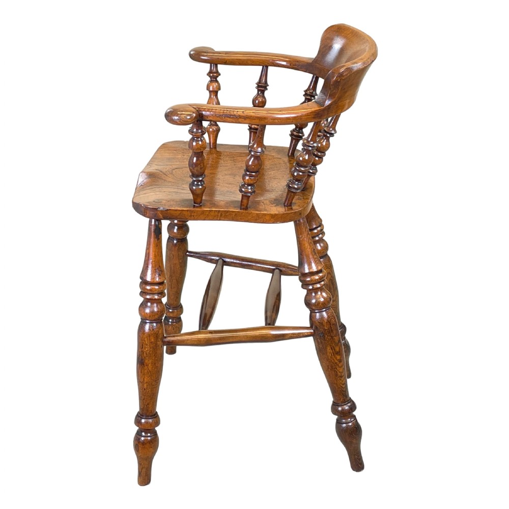 A 19th-century wooden clerk chair featuring a curved horseshoe backrest, turned spindles, a shaped saddle seat, and tall turned legs with double stretchers. View VII