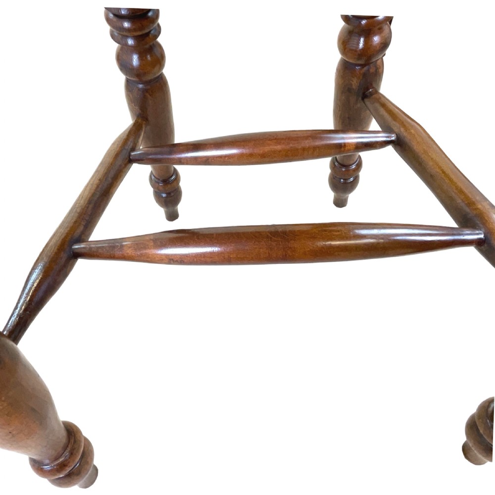 A 19th-century wooden clerk chair featuring a curved horseshoe backrest, turned spindles, a shaped saddle seat, and tall turned legs with double stretchers. View X