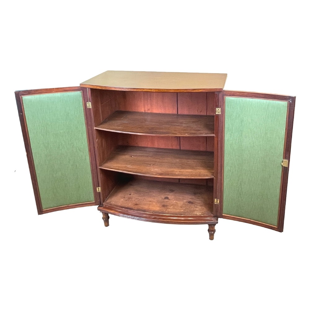 A Regency period bow-fronted mahogany side cabinet featuring two green fabric-panelled doors and turned legs. View II