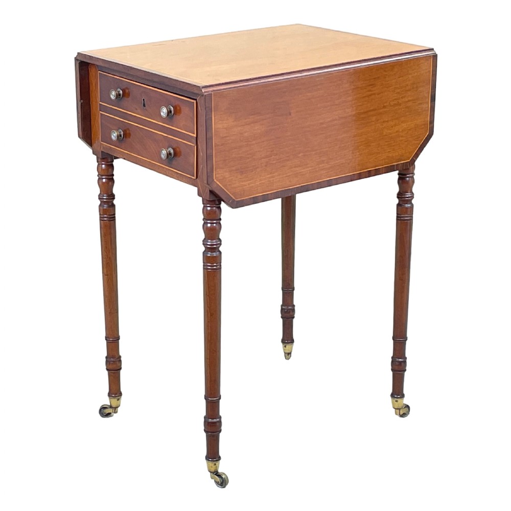 A small Georgian mahogany Pembroke table featuring two drawers with brass handles, fine stringing inlay, two drop leaves, and slender turned legs on brass castors. View II